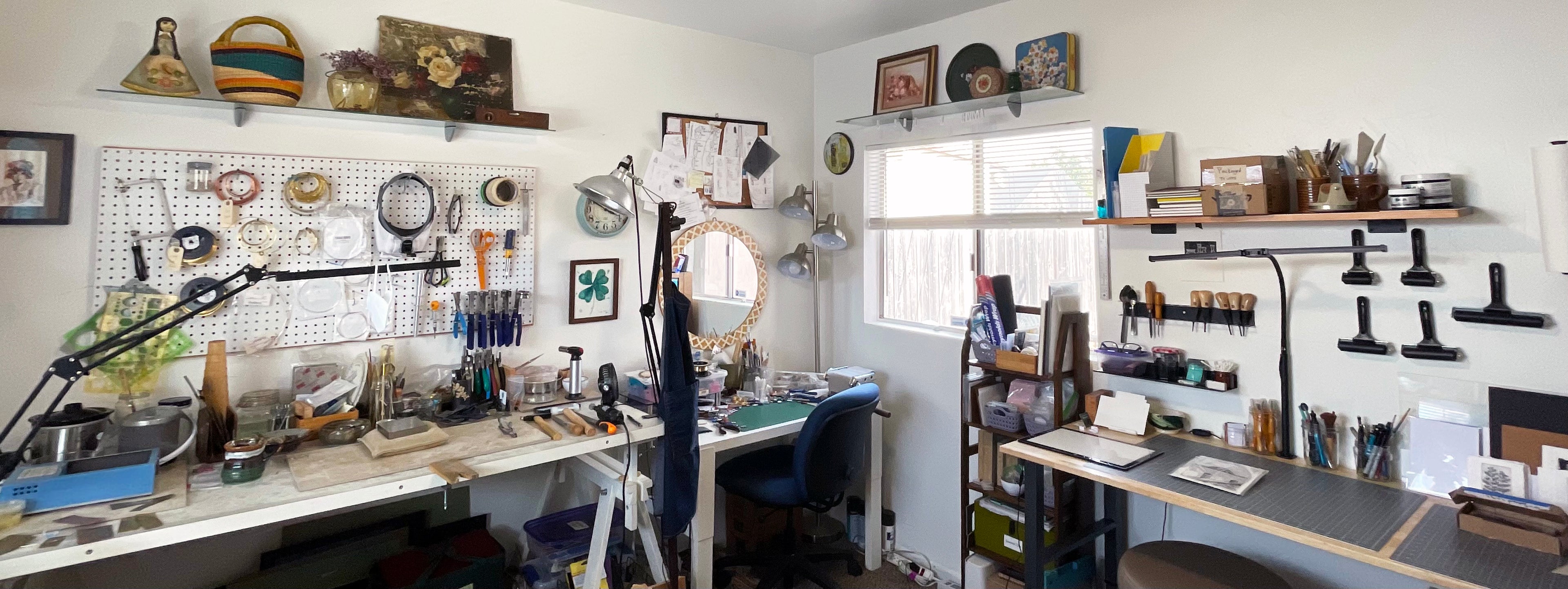 A wide interior shot of JAX Atelier's jewelry and printmaking studio with multiple workbenches, shelves, tools, hanging equipment, and decorative items.