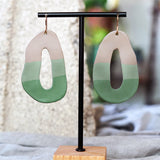 Pair of artsy polymer clay earrings with taupe and green gradient on a black stand. Made by Jax Atelier.